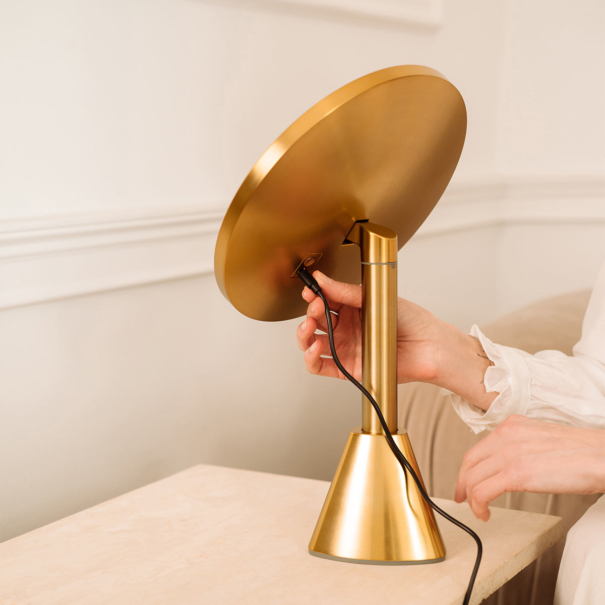 Gold rechargeable vanity mirror luxury being adjusted by a hand on a neutral background