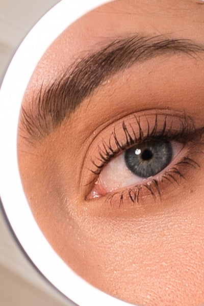 Close-up of a person's eye with detailed makeup view in lighted makeup mirror set