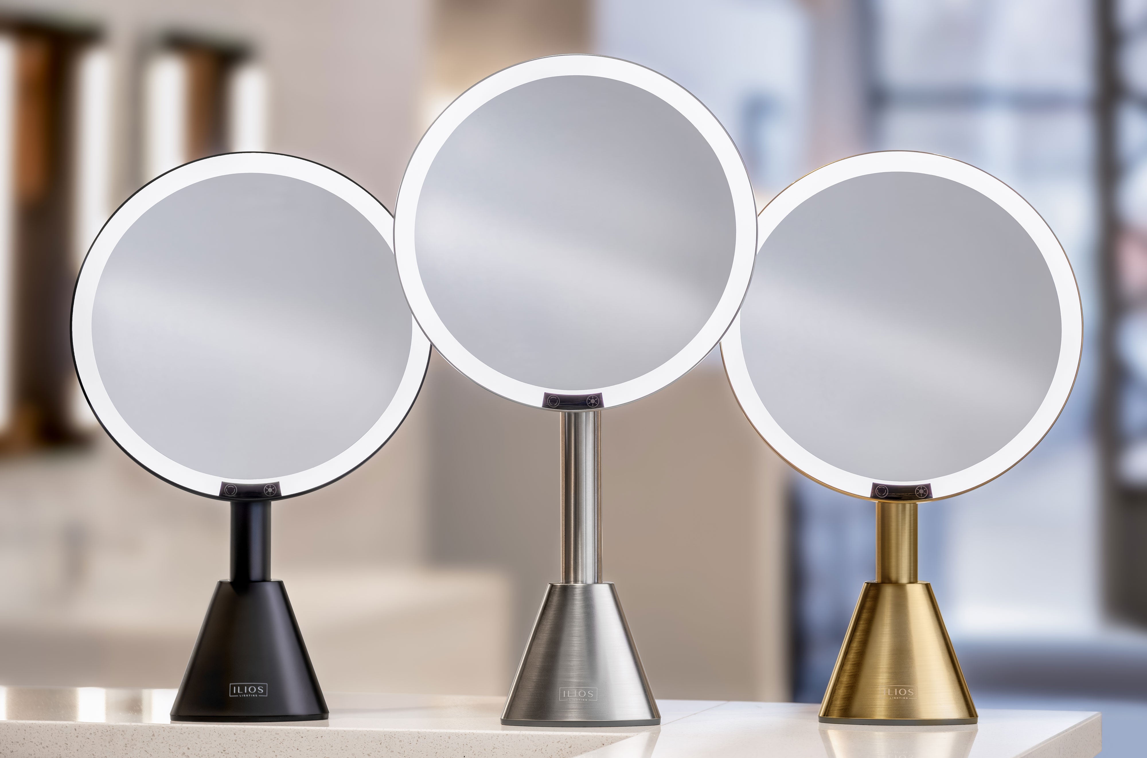 Three round luxury vanity mirrors with light with illuminated edges on stands in a blurred indoor setting