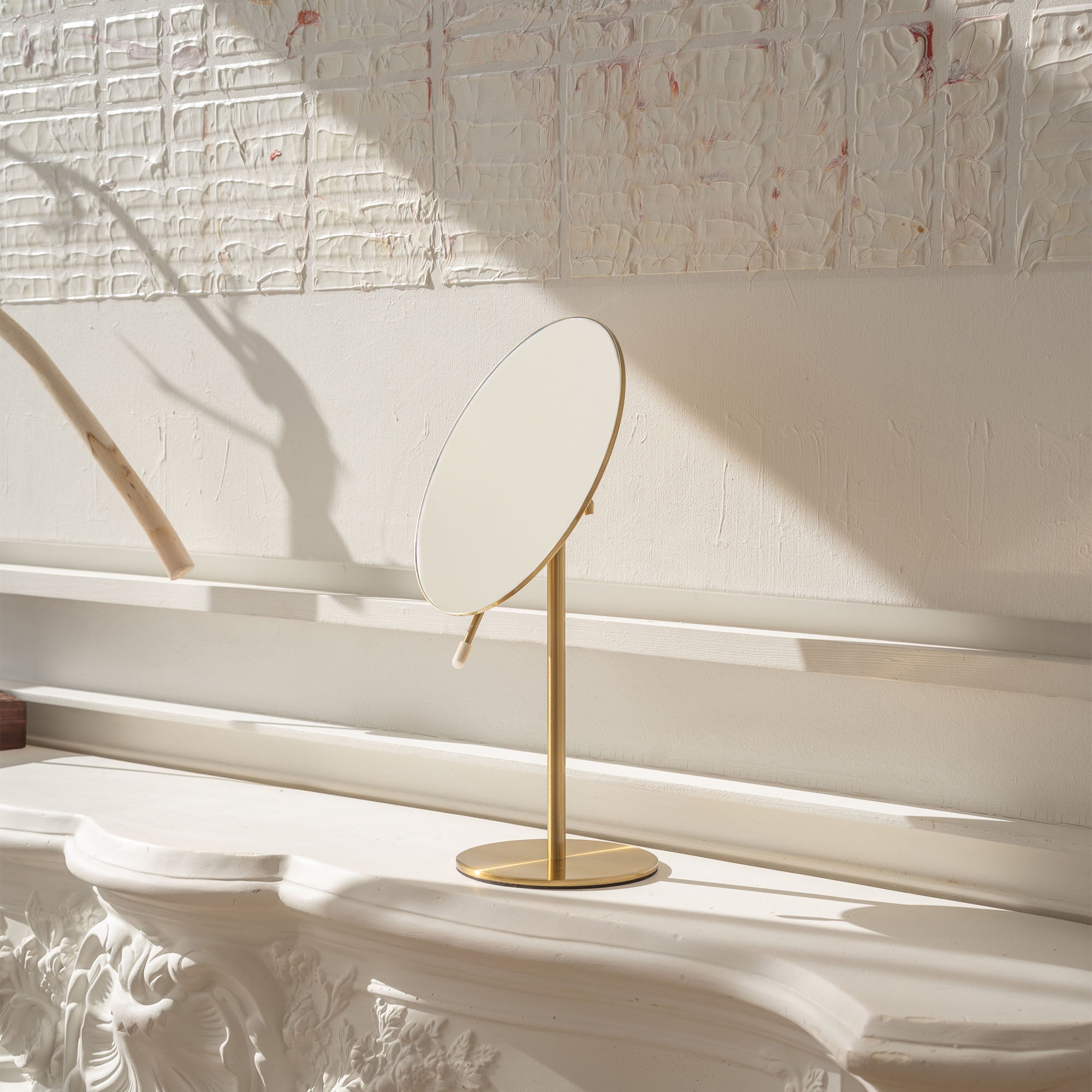 Gold stand mirror on a white surface with a textured white wall background_#Silver_Gold