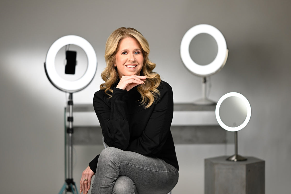 Woman sitting between three ring lights in a studio setting
