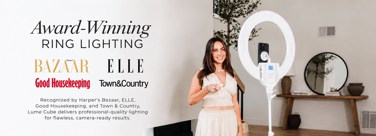 A woman in a white dress stands indoors beside a large white ring light, with promotional text on the left reading 'Award-Winning Ring Lighting' and logos for Bazaar, Elle, Good Housekeeping, and Town & Country.